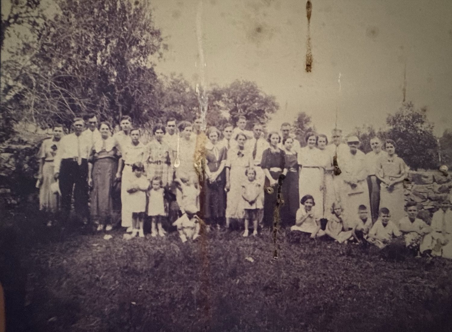 A large Tucker family gathering in front of a stone wall, about the 1920s–1930s